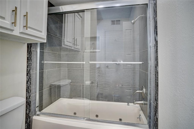 bathroom with shower / bath combination with glass door and toilet