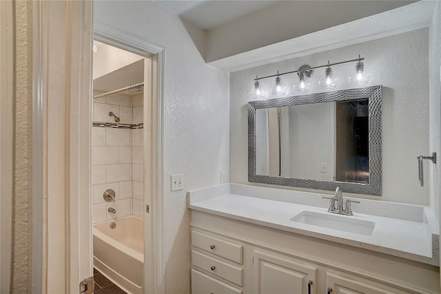 bathroom with tiled shower / bath combo and vanity