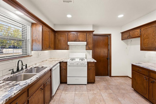 kitchen featuring light stone countertops, sink, white appliances, decorative backsplash, and light tile patterned flooring