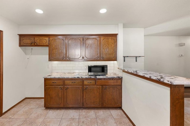 kitchen with kitchen peninsula, backsplash, and light tile patterned flooring