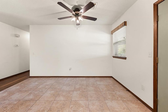 empty room with ceiling fan and light tile patterned flooring