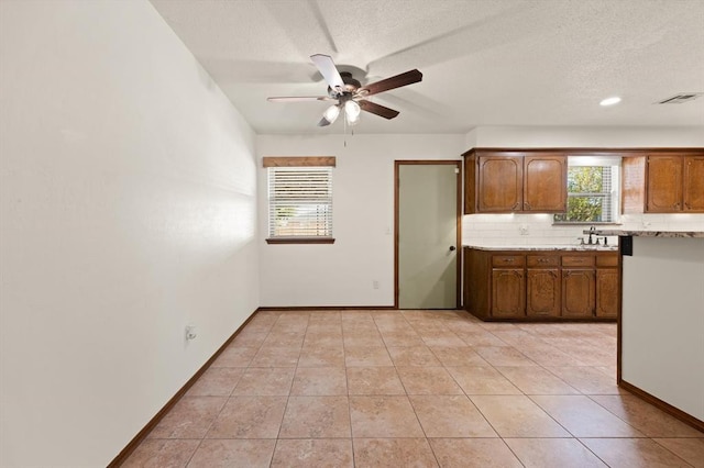 kitchen with light tile patterned floors, a textured ceiling, tasteful backsplash, and ceiling fan