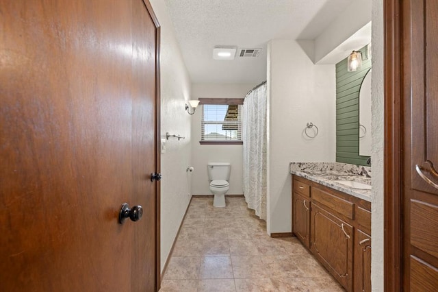 bathroom featuring a textured ceiling, vanity, toilet, and tile patterned floors