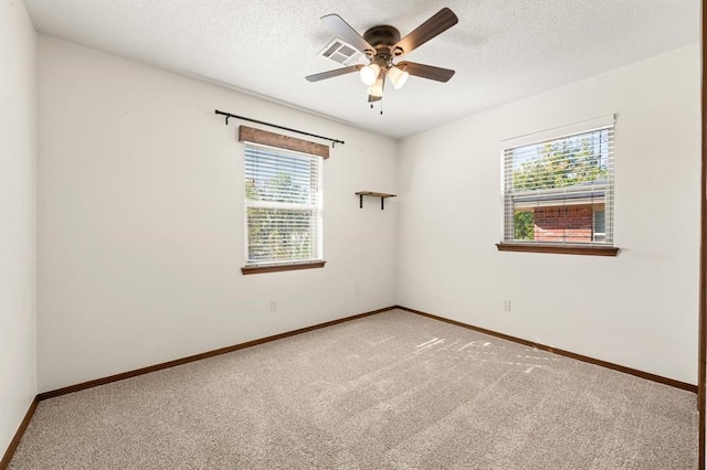 carpeted spare room featuring ceiling fan, a healthy amount of sunlight, and a textured ceiling