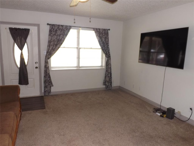 unfurnished living room featuring carpet flooring, ceiling fan, and a textured ceiling