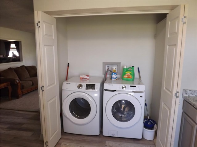 laundry room with washing machine and clothes dryer and hardwood / wood-style floors