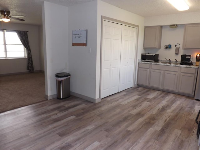 kitchen featuring gray cabinetry, ceiling fan, wood-type flooring, and a textured ceiling