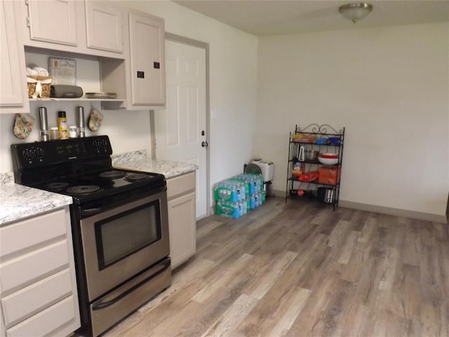 kitchen featuring white cabinets, light hardwood / wood-style floors, light stone countertops, and black electric range