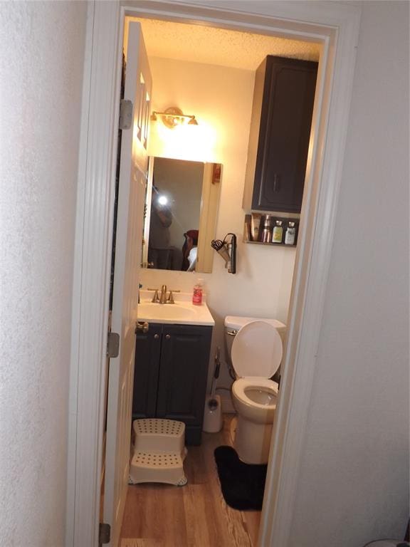 bathroom with hardwood / wood-style floors, vanity, and toilet