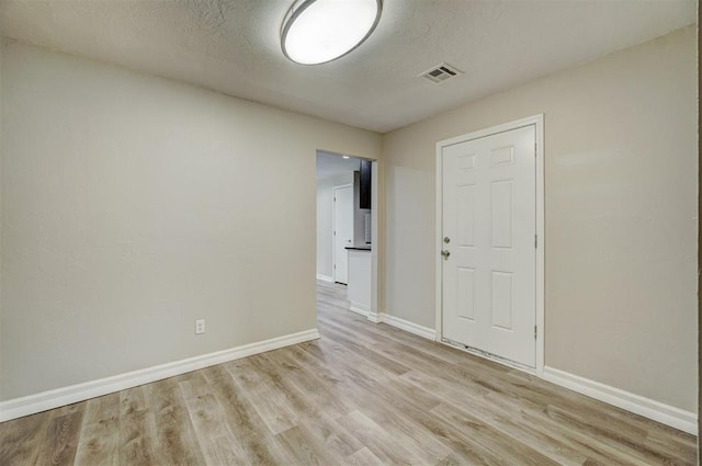 spare room with a textured ceiling and light hardwood / wood-style floors