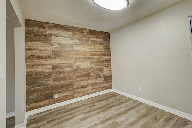 spare room with wood-type flooring and wooden walls