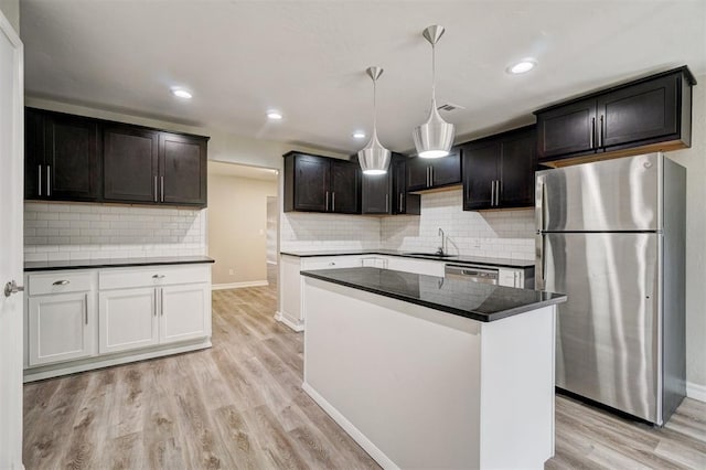 kitchen with sink, hanging light fixtures, decorative backsplash, light hardwood / wood-style floors, and stainless steel appliances