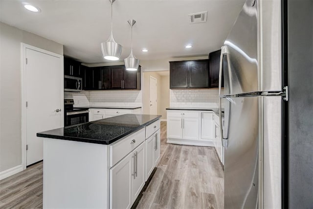 kitchen with backsplash, stainless steel appliances, white cabinets, light hardwood / wood-style floors, and a kitchen island