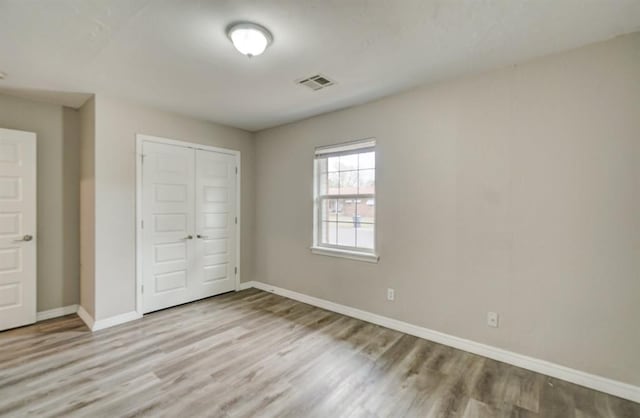 unfurnished bedroom with light hardwood / wood-style flooring and a closet