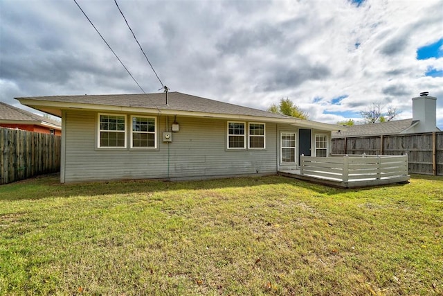 back of property with a deck and a yard