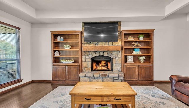 living room with a raised ceiling, a fireplace, and dark hardwood / wood-style floors