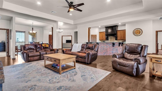 living room with ceiling fan with notable chandelier and dark wood-type flooring