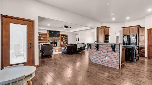 kitchen featuring dark hardwood / wood-style flooring, ceiling fan, a breakfast bar area, and black appliances