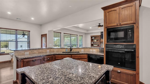 kitchen featuring black appliances, backsplash, a healthy amount of sunlight, and hardwood / wood-style floors