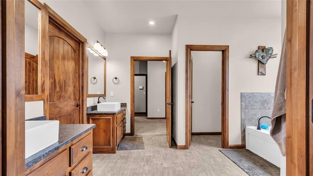 bathroom featuring wood-type flooring, vanity, and a tub to relax in