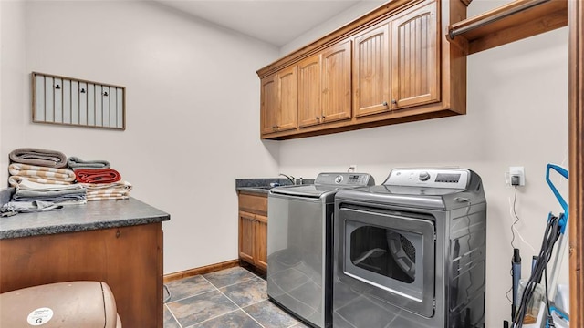 laundry area featuring washer and clothes dryer, cabinets, and dark tile patterned flooring