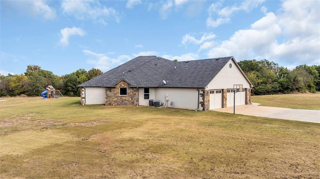 rear view of house with a playground, a garage, cooling unit, and a lawn