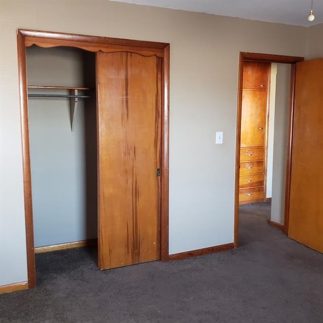 unfurnished bedroom featuring dark colored carpet and a closet