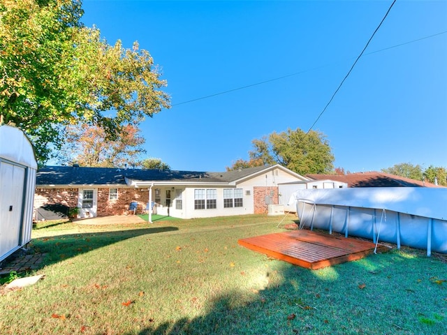 rear view of property featuring a lawn and a pool side deck