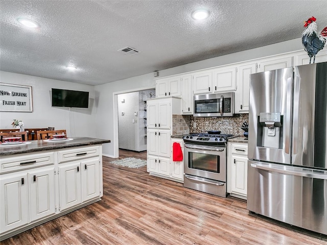 kitchen with white cabinets, a textured ceiling, and stainless steel appliances