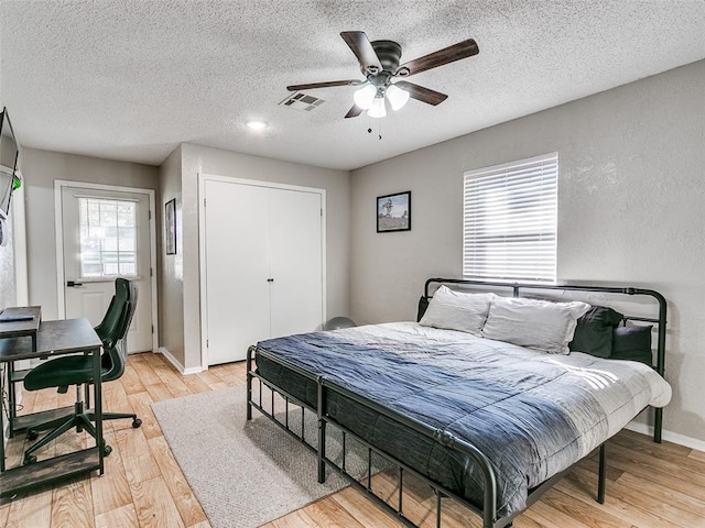 bedroom with a textured ceiling, light hardwood / wood-style floors, and ceiling fan