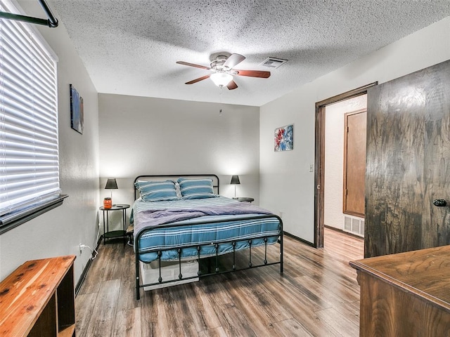 bedroom with a textured ceiling, hardwood / wood-style flooring, and ceiling fan