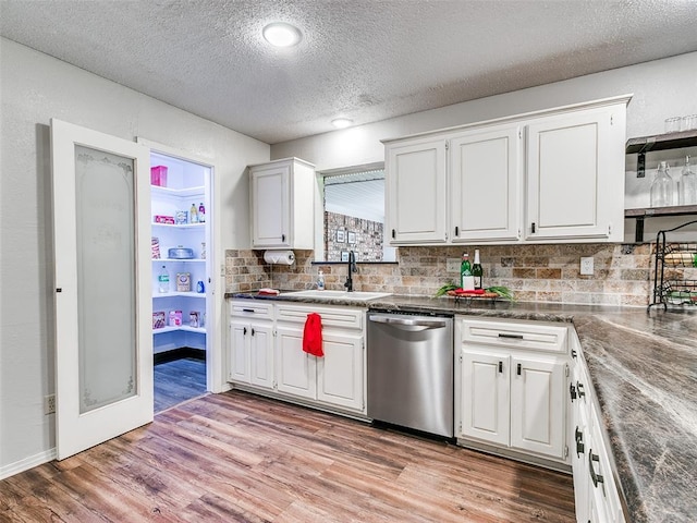 kitchen featuring stainless steel dishwasher, a textured ceiling, sink, light hardwood / wood-style flooring, and white cabinets