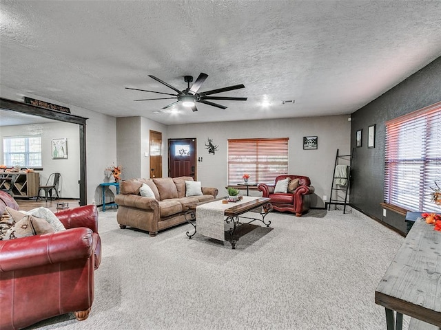 living room featuring carpet flooring, ceiling fan, and a textured ceiling