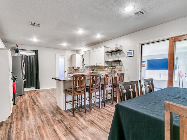 dining area with light hardwood / wood-style floors and a textured ceiling