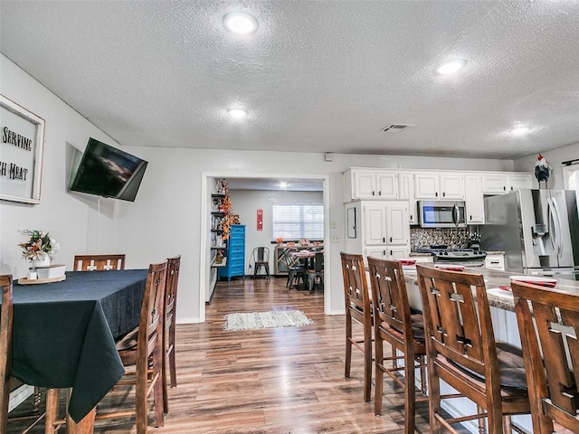 dining space with a textured ceiling and hardwood / wood-style flooring