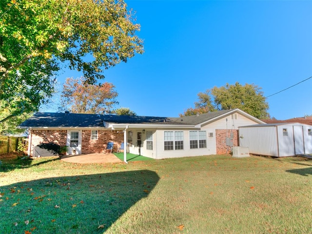 back of property with a lawn, a patio, and a storage shed