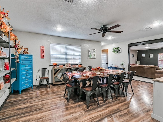 dining space with ceiling fan, wood-type flooring, and a textured ceiling