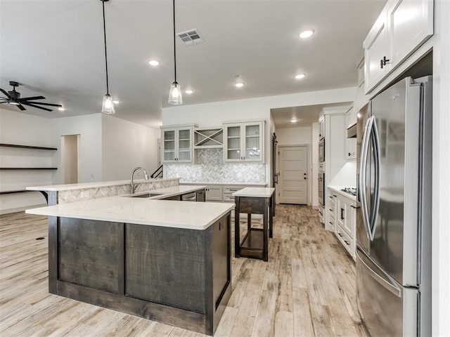 kitchen featuring ceiling fan, sink, stainless steel appliances, backsplash, and decorative light fixtures