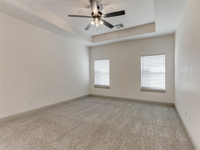 carpeted empty room featuring a tray ceiling and ceiling fan