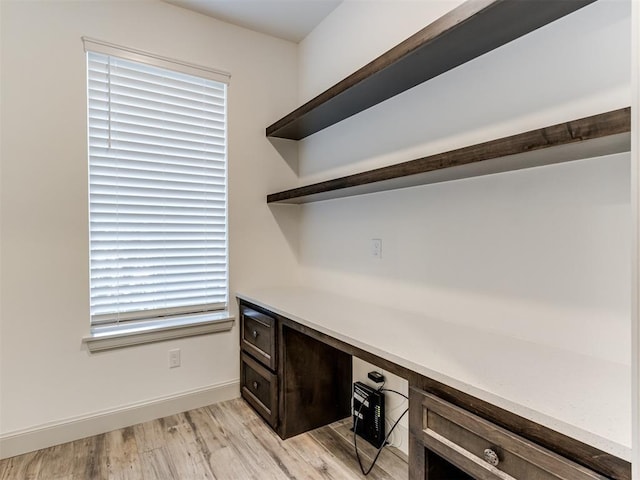 home office with built in desk and light hardwood / wood-style flooring