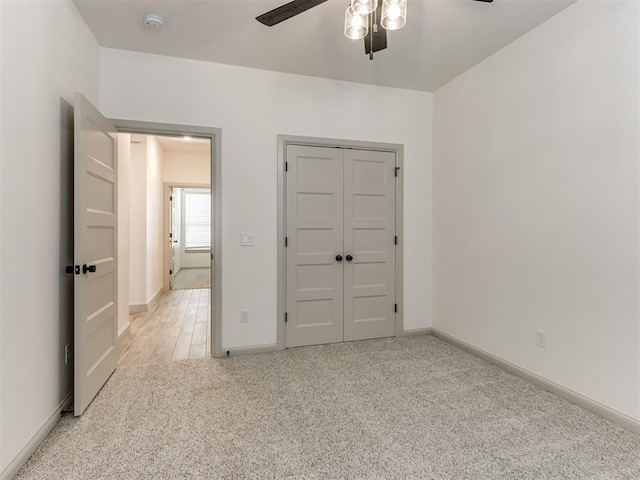 unfurnished bedroom featuring ceiling fan, a closet, and light carpet