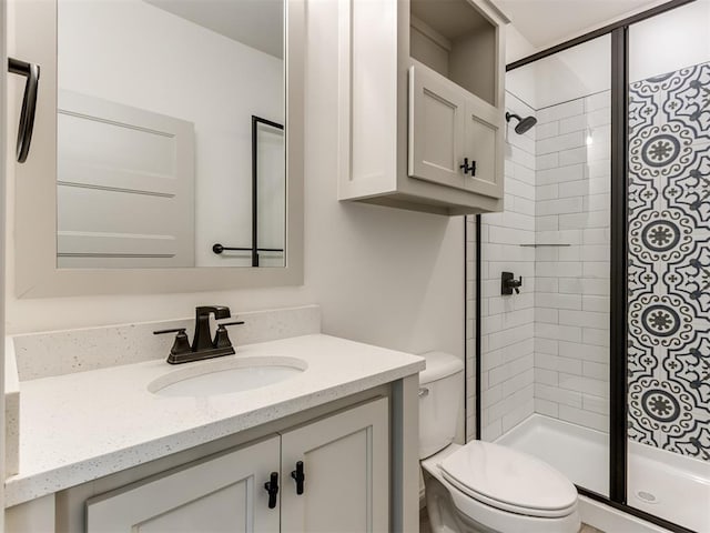 bathroom featuring tiled shower, vanity, and toilet