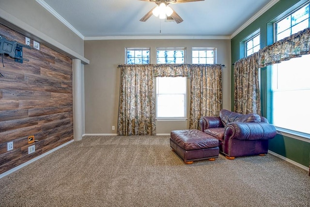 living area featuring carpet flooring, ceiling fan, ornamental molding, and wooden walls