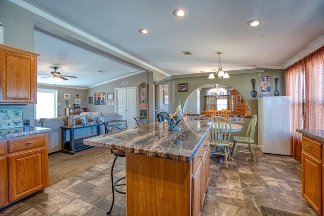 kitchen with a center island, lofted ceiling, a kitchen breakfast bar, ornamental molding, and white fridge