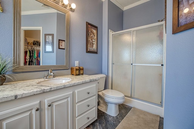 bathroom featuring ornamental molding, vanity, hardwood / wood-style flooring, toilet, and a shower with shower door