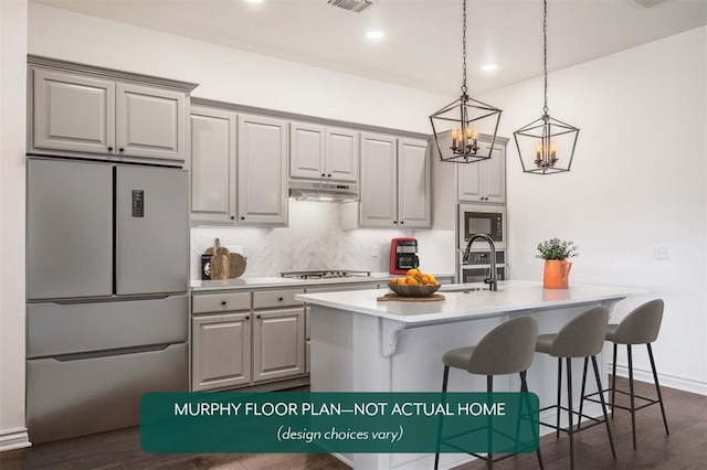 kitchen with a kitchen breakfast bar, sink, appliances with stainless steel finishes, and dark wood-type flooring