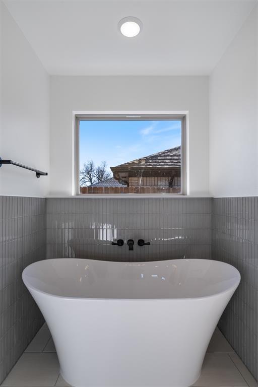 bathroom with a bathtub, plenty of natural light, tile walls, and tile patterned floors