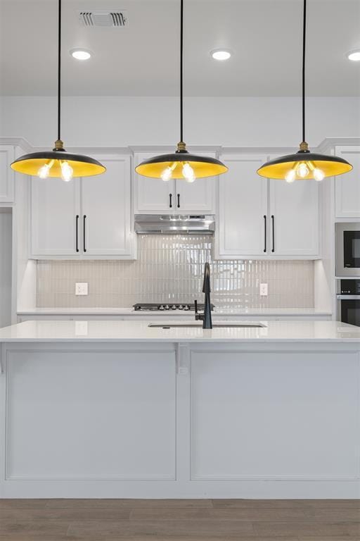 kitchen featuring decorative light fixtures, white cabinetry, and stainless steel oven