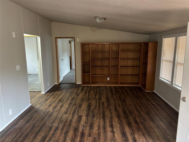 unfurnished room featuring lofted ceiling and dark wood-type flooring