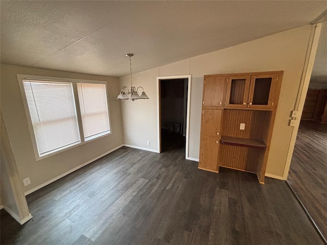 unfurnished dining area with a textured ceiling, dark wood-type flooring, vaulted ceiling, and a notable chandelier